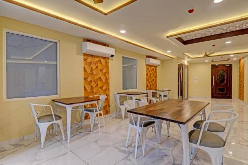 a restaurant with wooden tables and white chairs at Hotel Heera Grand in Lucknow