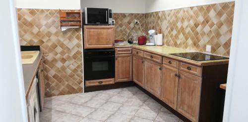 a kitchen with wooden cabinets and a black refrigerator at Maison familiale Jardin parking, 10 min plage, 1* in Saint-Cyr-sur-Mer