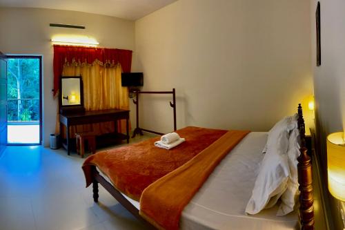1 dormitorio con cama, escritorio y espejo en Green View, en Thekkady