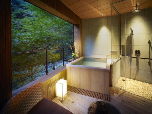 a bath tub in a room with a large window at Fudoguchikan in Izumi-Sano