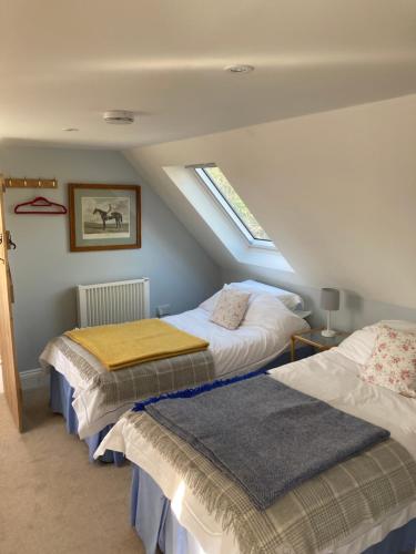 a attic room with two beds and a window at Barn Flat overlooking beautiful Dorset vale in Sherborne