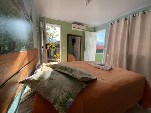 um quarto com uma cama e uma grande janela em Pousada Platôdasilhas em Angra dos Reis