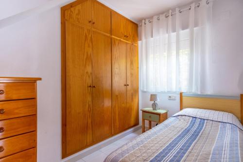 トレビエハにあるEspanatour LOS BALCONESのベッドルーム1室(ベッド1台付)、木製キャビネットが備わります。