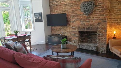 a living room with a couch and a brick wall at Beautiful Garden Apartment in Leafy St Leonards 5 Mins to Beach in St. Leonards