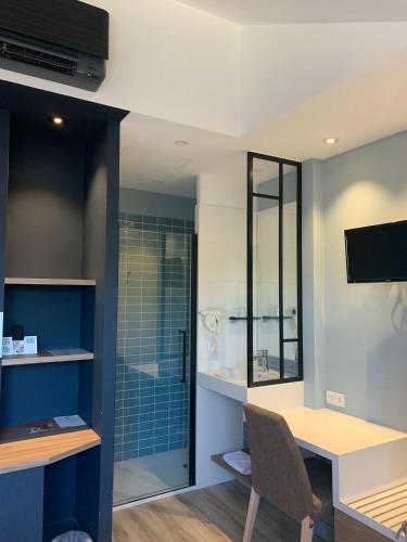 a bathroom with a desk and a glass shower at Logis Hôtel Domaine du Moulin Cavier - Restaurants & Spa in Avrillé