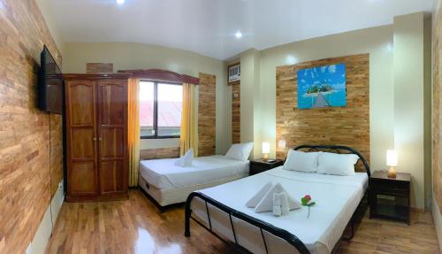 a bedroom with two beds and a large window at Mabini Hotel in Mambajao