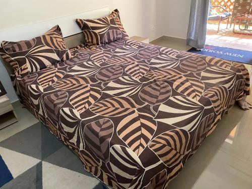 un letto con piumone e cuscini marroni e neri di HÊCHÉLOGE a Bandraboua