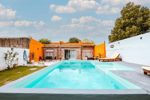 una piscina al aire libre con un edificio naranja y blanco en El Destino Casa de Descanso en Tandil