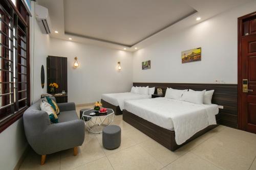 a hotel room with two beds and a chair at Hanoi Airport Suites Hostel & Travel in Hanoi