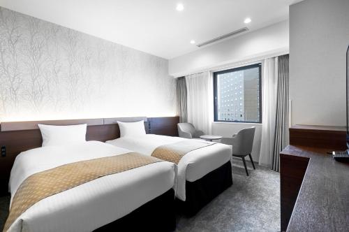 札幌市にあるダイワロイネットホテル札幌中島公園のベッド2台とデスクが備わるホテルルームです。