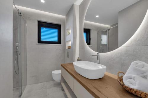ein weißes Badezimmer mit einem Waschbecken und einem Spiegel in der Unterkunft Villa Smilje in Pisak