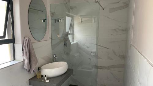 a white bathroom with a sink and a mirror at The Chameleon Stay @107 in Centurion