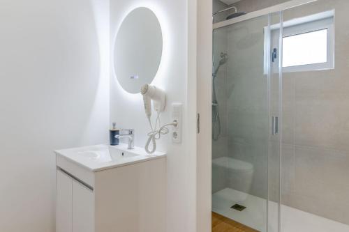 a white bathroom with a sink and a shower at 7 Mares in Póvoa de Varzim