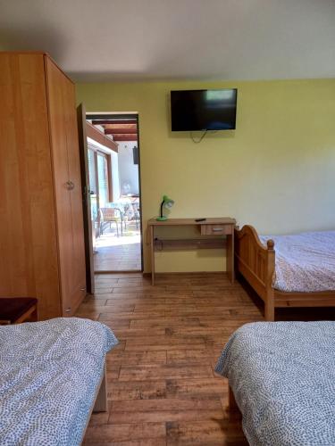 a bedroom with two beds and a television on the wall at Chata Kurpiowska in Nowogród