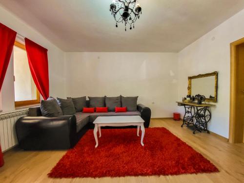 a living room with a black couch and a red rug at Nera-etwa Konjic 2 room in Konjic