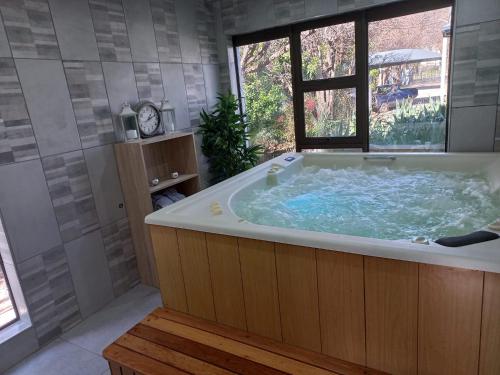 a large bath tub in a bathroom with a window at St Eve Lodge & Spa in Bloemfontein