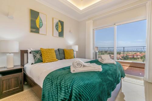 1 dormitorio con 1 cama con manta verde y ventana en Casa Makin at Boa Vista Golf Resort, Bayview Village en Lagos