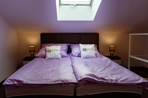 Un dormitorio con una cama con sábanas y almohadas púrpuras. en Rivendell Mielno en Mielno