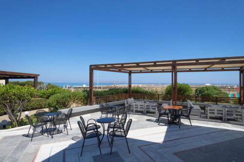 a patio with chairs and tables and a view of the ocean at Sol Marina Beach Crete in Gouves