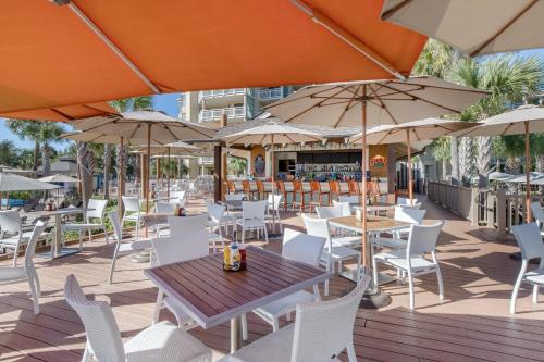an outdoor patio with tables and chairs and umbrellas at Omni Hilton Head Oceanfront Resort in Hilton Head Island