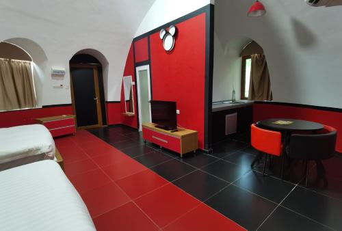 a room with a bed and a tv and a red wall at MyRus Resort Langkawi in Pantai Cenang