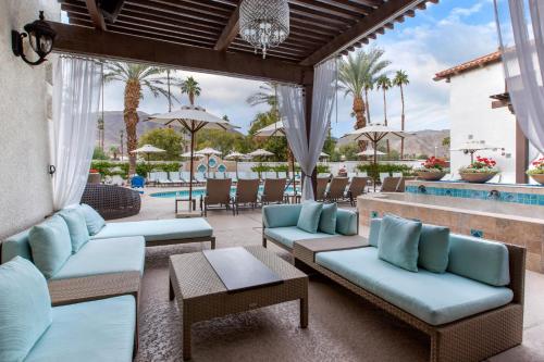 a patio with blue couches and a pool at Omni Rancho Las Palmas Resort & Spa in Rancho Mirage