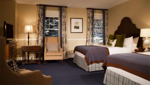 a hotel room with two beds and a chair at Omni Bretton Arms Inn at Mount Washington Resort in Bretton Woods