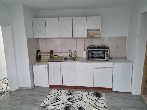 a small kitchen with a sink and a microwave at Apartman „Škobić” in Višegrad