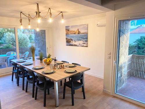 a dining room with a large wooden table and chairs at L'Artmonie - Climatisé - Jardin - Centre-ville - Plage in Perpignan