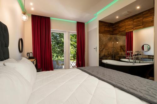 1 dormitorio con 1 cama blanca grande y bañera en Angelo Spa Resort en Sankt Andreasberg