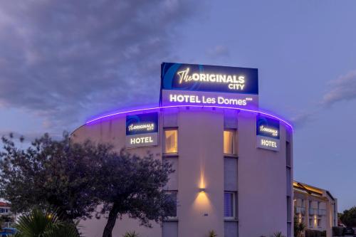 a hotel building with a sign on top of it at The Originals City, Hôtel Les Dômes, Perpignan Sud Saleilles in Perpignan