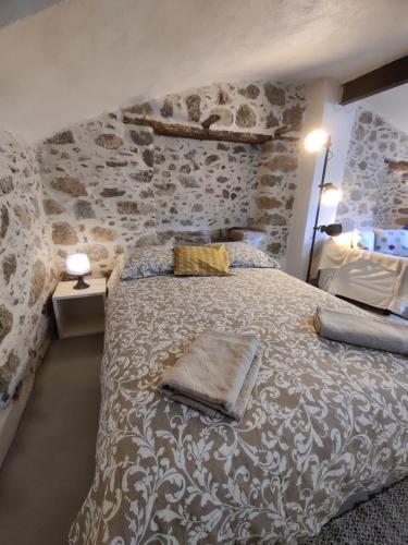 - une chambre avec un grand lit et un mur en pierre dans l'établissement Rendez-vous sous le tilleul, en Cevennes., à Molières-Cavaillac