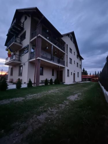 a large white building with balconies and a yard at Pensiunea Agroturistica ANCA&IOANA in Bălceşti