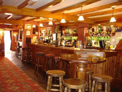 a bar with tables and stools in a restaurant at The Four Alls Inn in Market Drayton