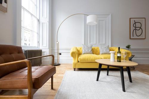 a living room with a yellow couch and a table at Dragon Suites Luxury Serviced Apartments at Alva Street in Edinburgh