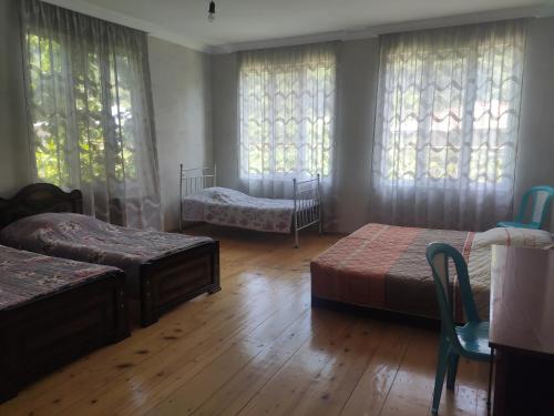 a bedroom with two beds and two chairs and windows at Family house in Racha, Oni in Oni