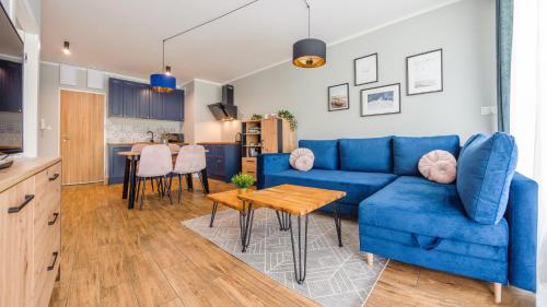een woonkamer met een blauwe bank en een tafel bij Apartamenty Sun & Snow Gąski in Gąski