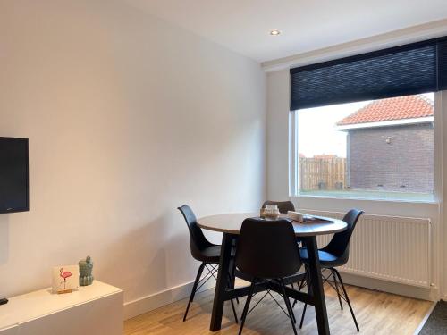 a dining room with a table and chairs and a window at Dorpsweg 18 nummer 5 in Callantsoog