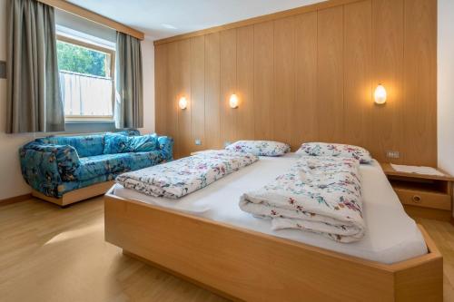 a bedroom with a large bed and a blue couch at App Sonne Nr 21 in Lutago