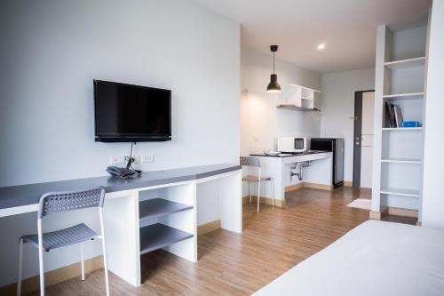 a living room with a desk with a tv on a wall at Vanilla Residence Chiangmai in Chiang Mai