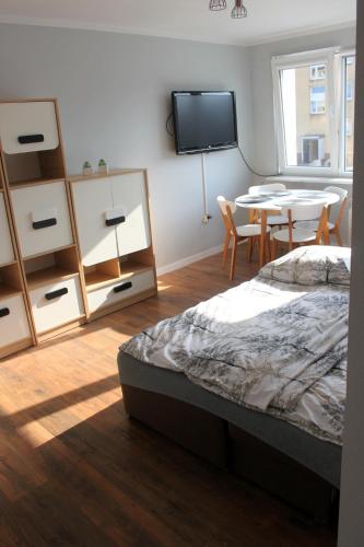 a bedroom with a bed and a table and a tv at Apartament Q Centrum Władysławowo z garażem in Władysławowo