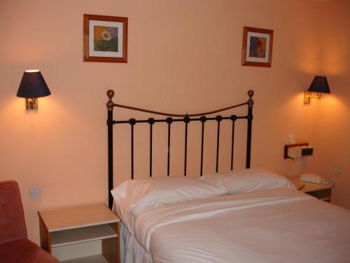 a bedroom with a bed with white sheets and two lamps at The Four Alls Inn in Market Drayton