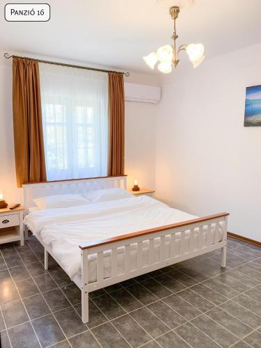 a bedroom with a large white bed with a window at Gosztonyi Villa in Siófok