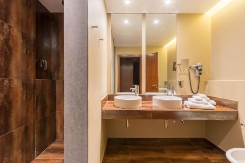 a bathroom with two sinks and a large mirror at NAU Salgados Palm Village - All Inclusive in Albufeira