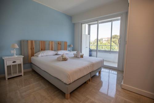 une chambre avec un grand lit et une grande fenêtre dans l'établissement La Casa Blu by Connexion, à Cannes