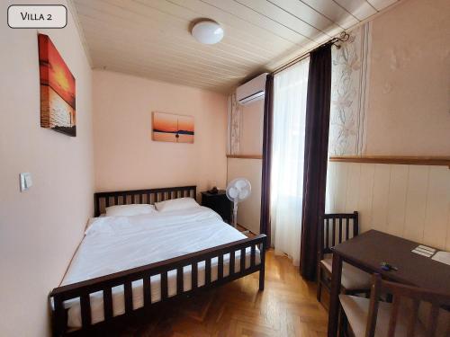 a bedroom with a bed and a table and a window at Gosztonyi Villa in Siófok