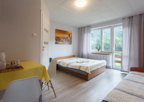 1 dormitorio con cama, mesa y ventana en U podnóża Kotarza, en Brenna