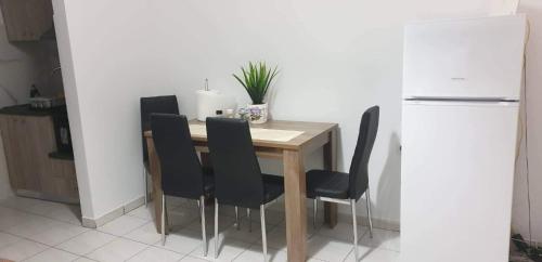 uma mesa de jantar com cadeiras pretas e um frigorífico branco em GEORGE & ELENA APARTMENTS em Amoudara Herakliou