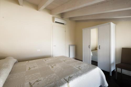a bedroom with a white bed and a closet at Corte Elvira in Manerba del Garda