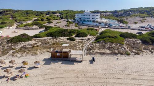 an aerial view of a beach with chairs and a building at Hotel Maysi in Playa Migjorn